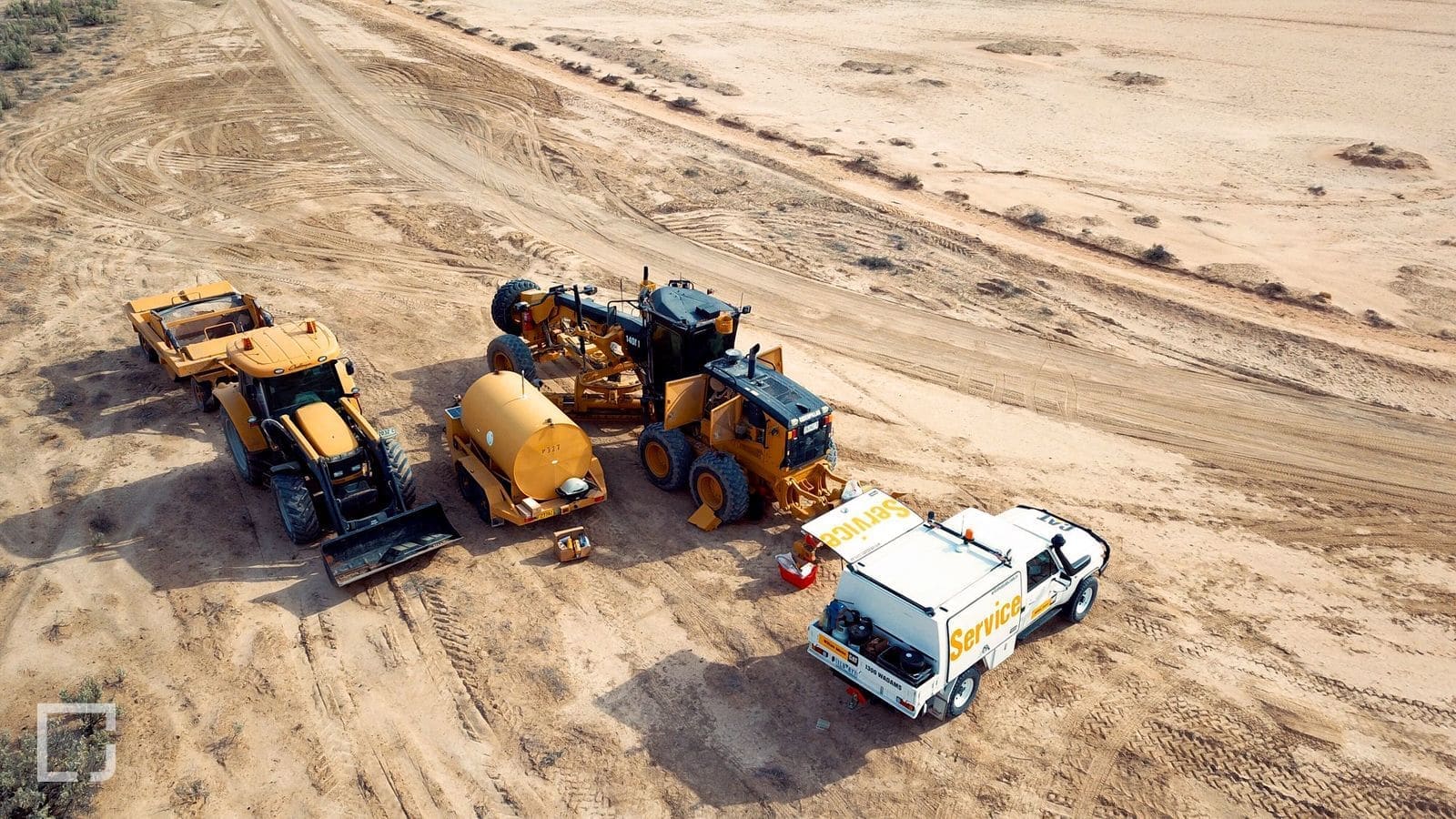 Aerial view of a Hidrive service fleet parked beside earthmoving machines on a red-dirt site