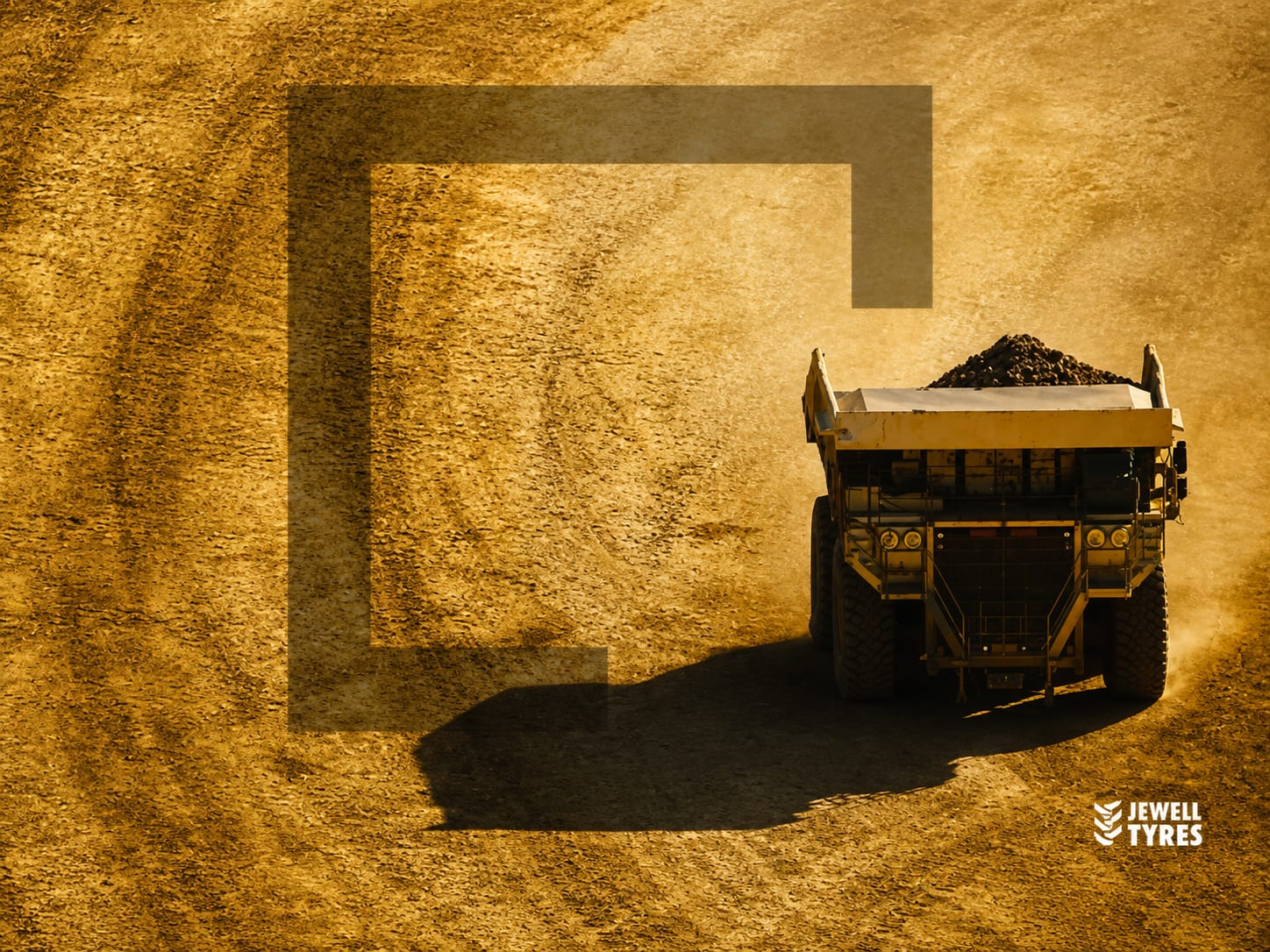 A loaded mining haul truck on an ochre haul road, shot from above