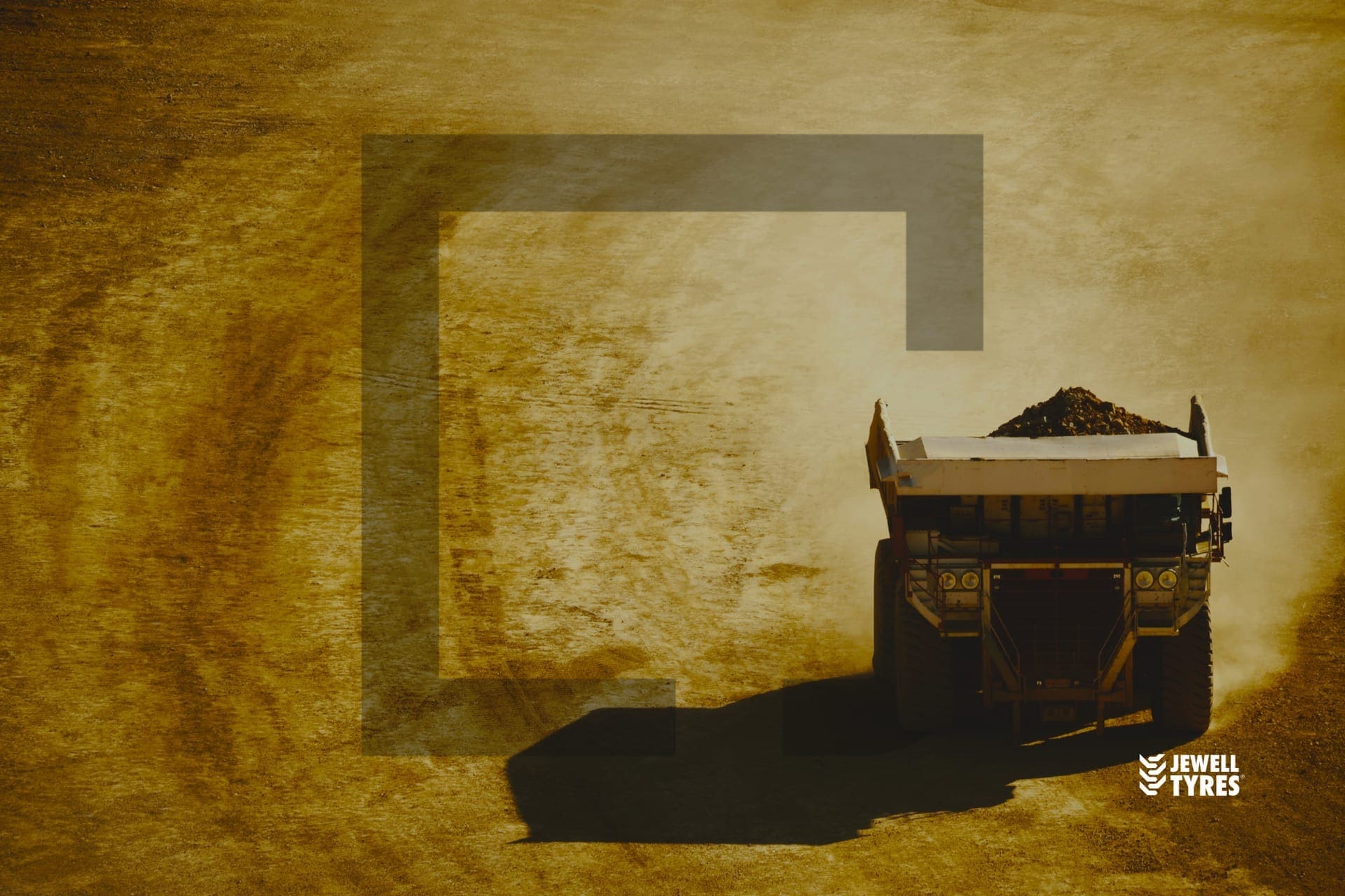 A haul truck crossing a mine site in dust and low sun, under the Jewell Tyres mark