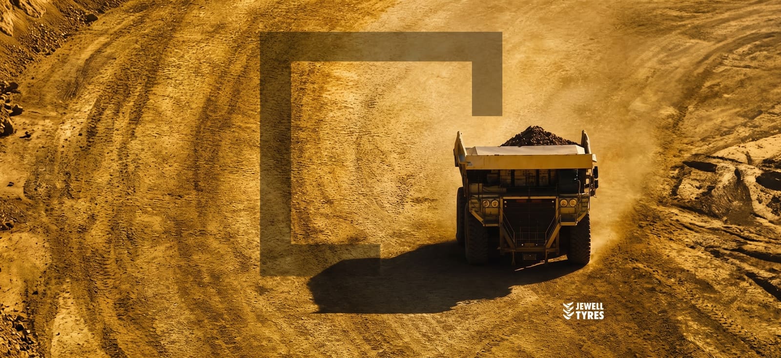 A Jewell Tyres haul truck on a mine road in golden dust, the Jewell bracket set into the ground